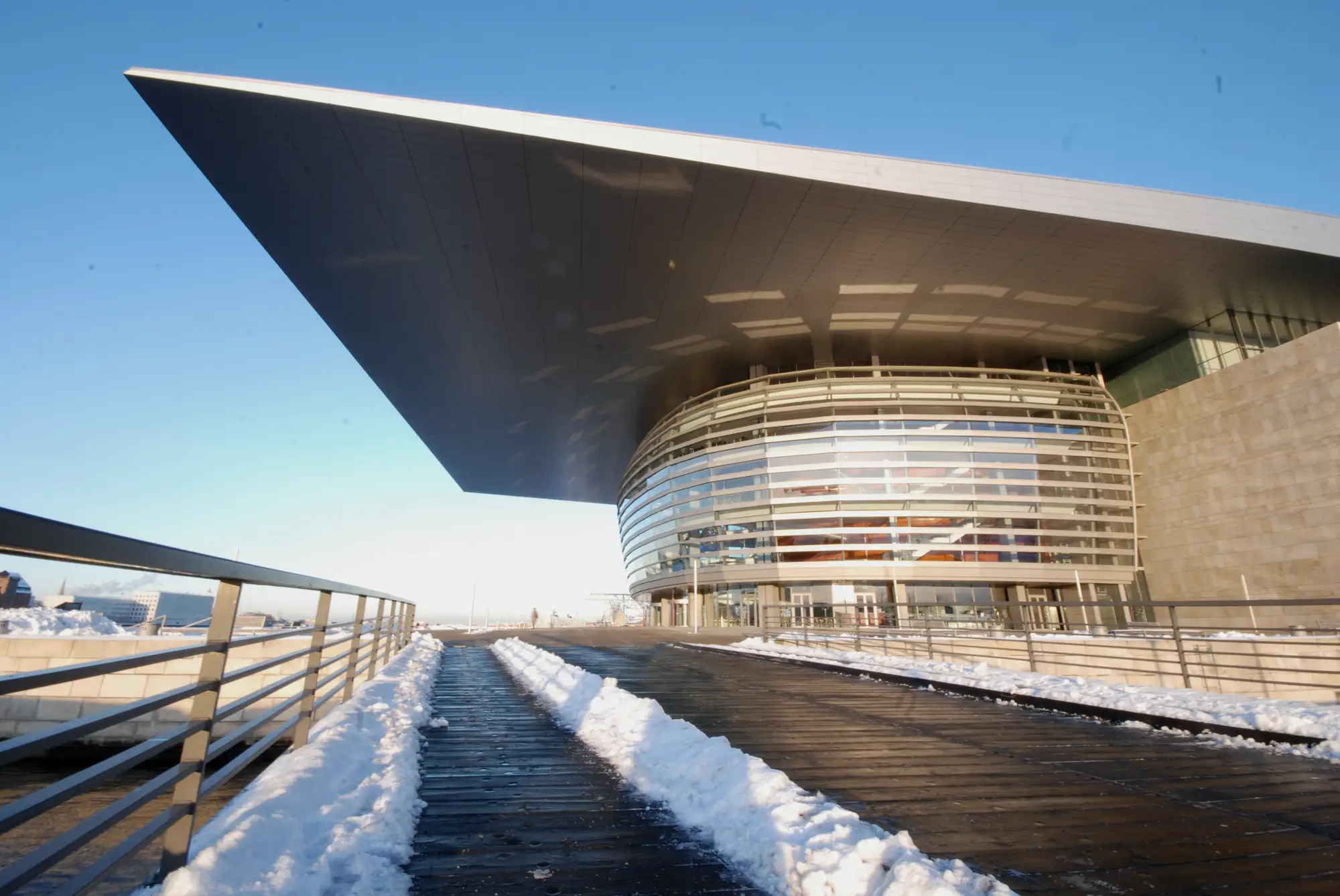A public waterfront promenade held clear of snow while the surrounding ground stays covered.