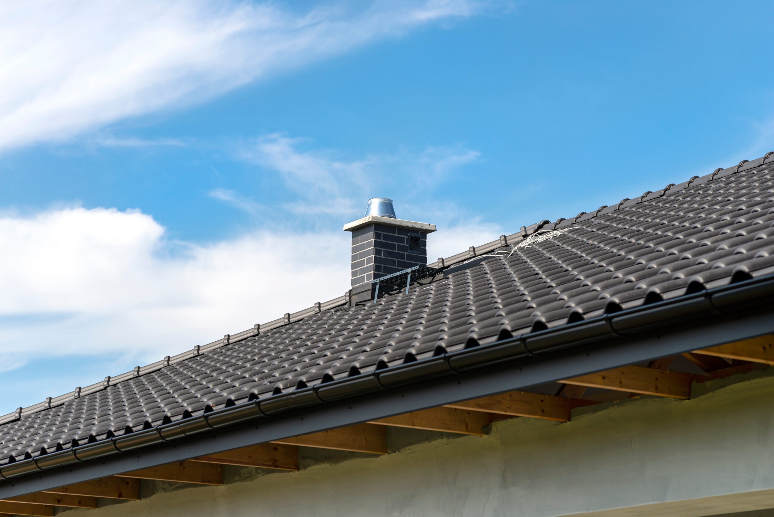 Roof, chimney and gutter beneath a clear blue sky