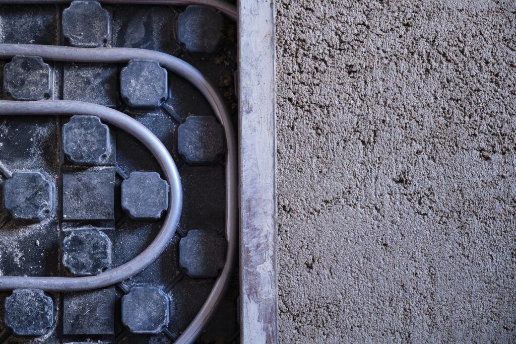 Underfloor heating installation beside a fresh concrete pour